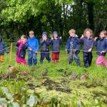 Students stood all around a pond