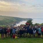 The whole group of students with the sea behind them