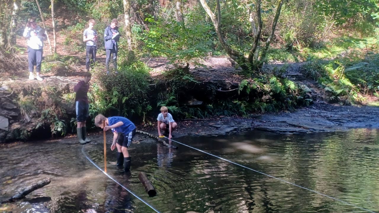 students in the river completing Geography work