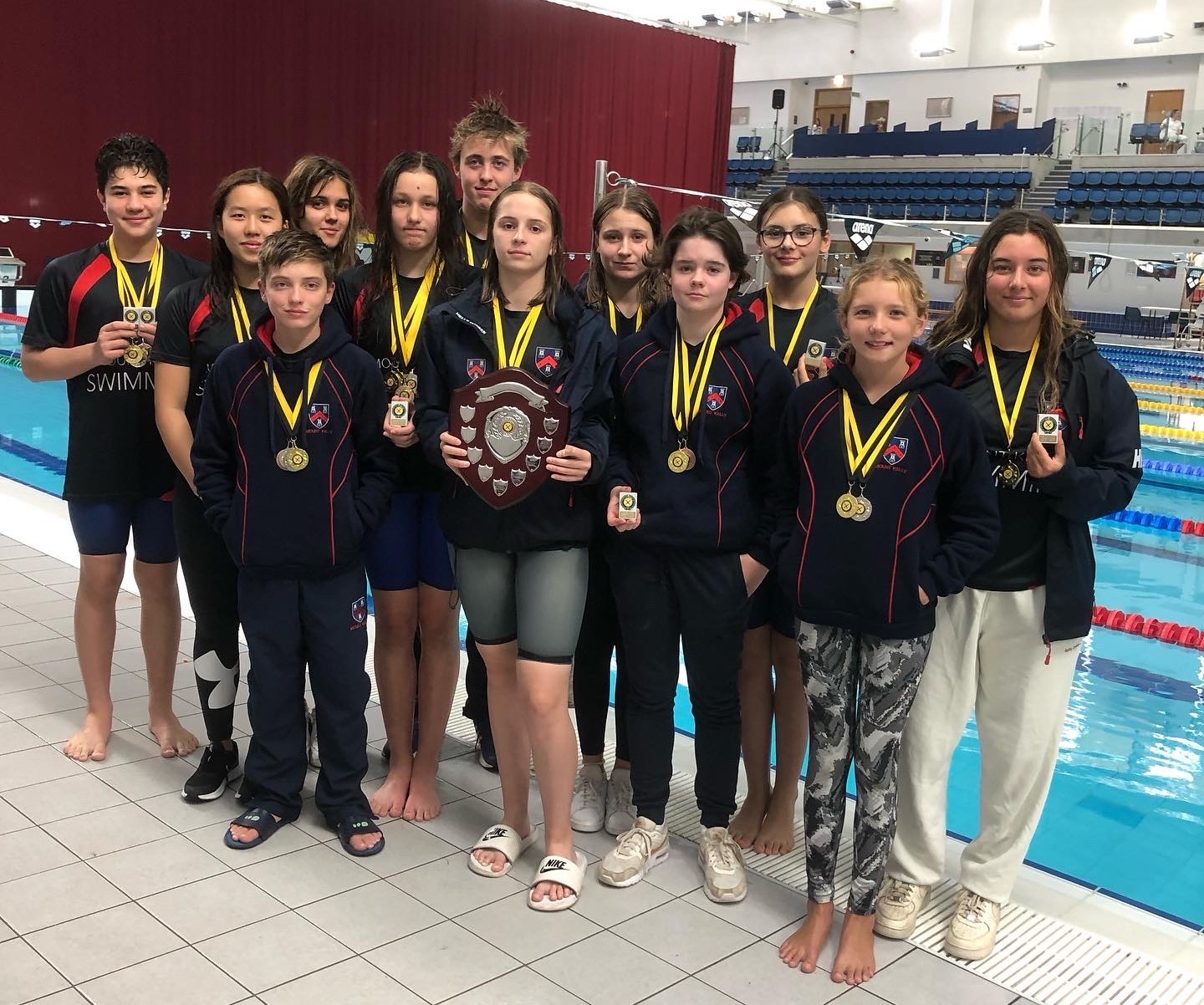 Students with their medals and awards at the swimming pool