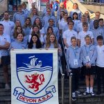 Devon ASA poster held with a group of student of