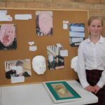 student stood next to art display