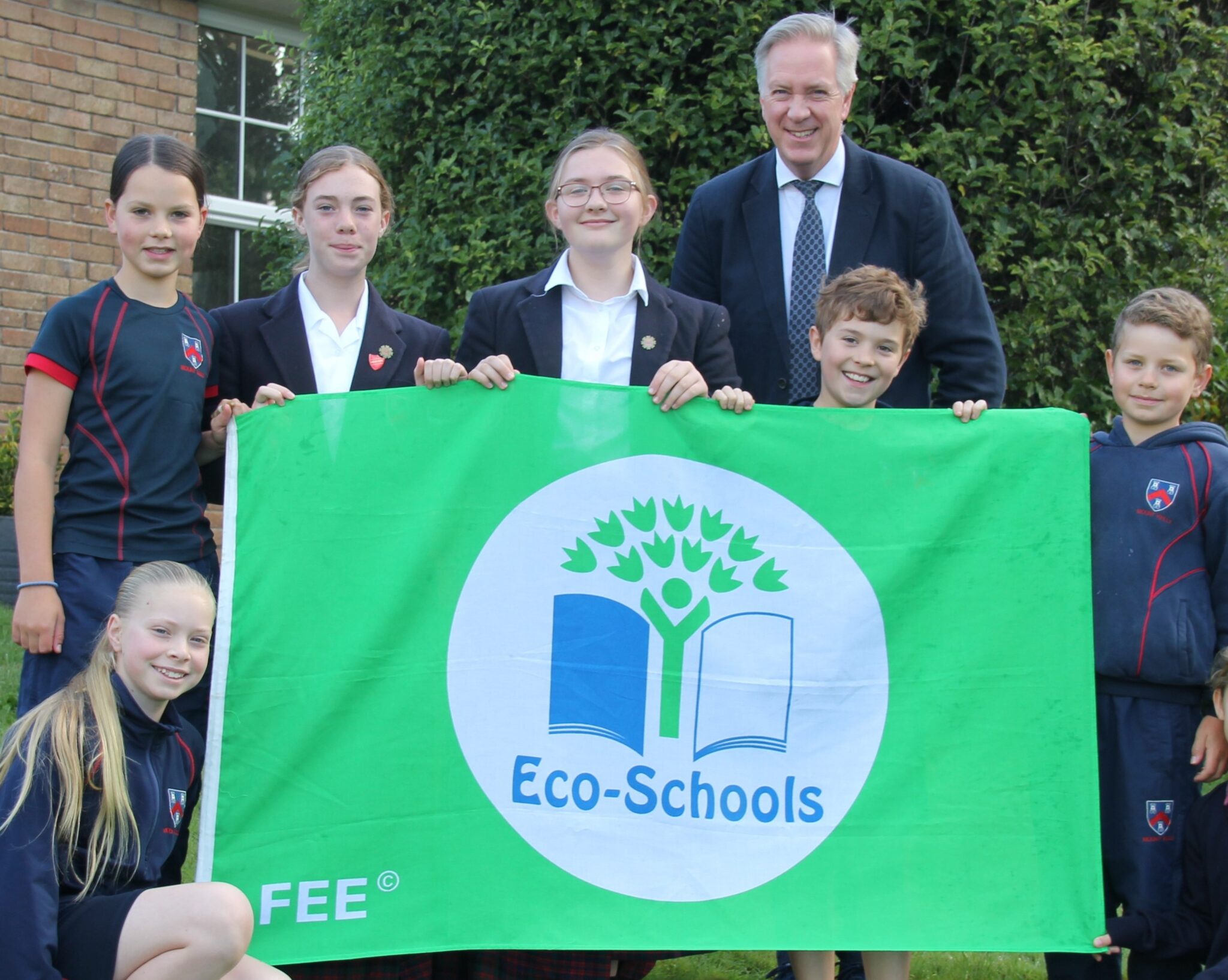 students and teacher holding an eco-schools flag