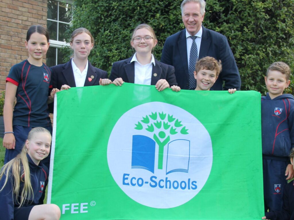 students and teacher holding an eco-schools flag