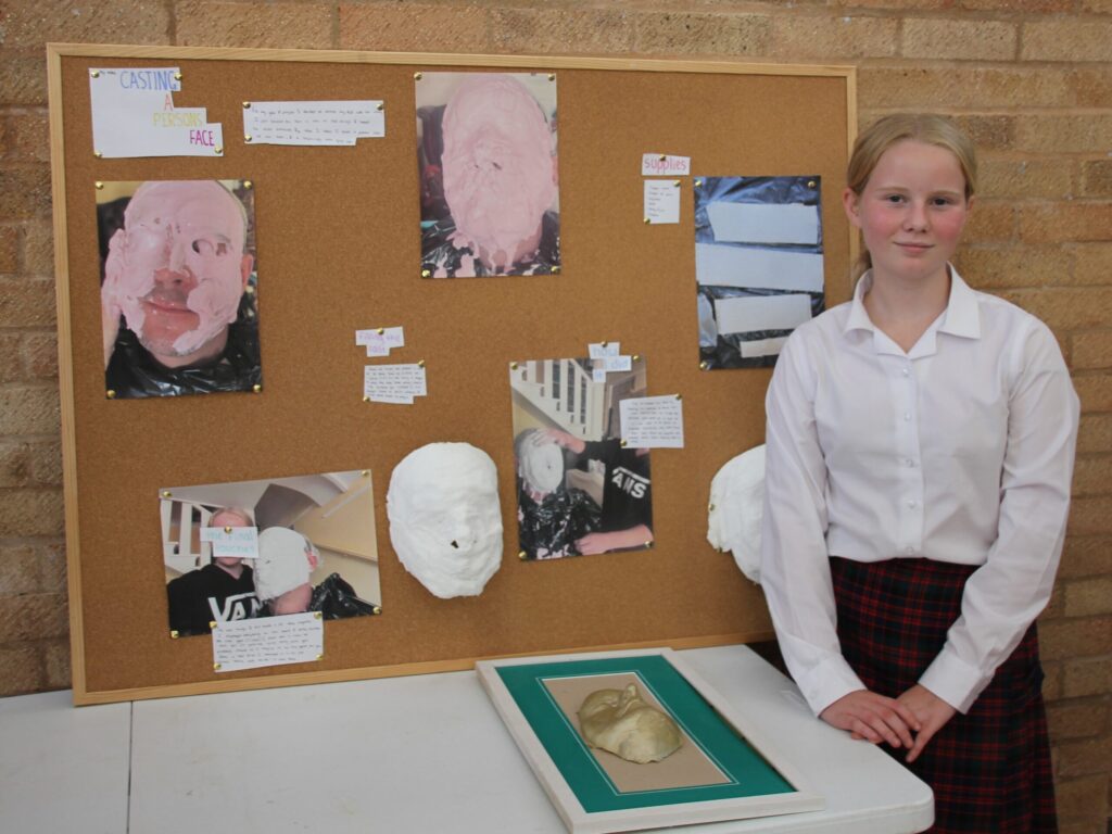 student stood next to art display